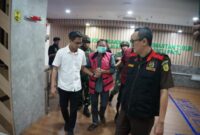 Keterangan: AS (tengah), eks Kadistamben Kukar 2010–2011, saat dibawa menuju ruang penahanan oleh penyidik Kejati Kaltim setelah resmi berstatus tersangka dalam perkara tambang ilegal di kawasan transmigrasi Tenggarong Seberang. (Kawalkaltim.com/Masruji)
