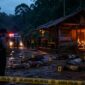 Keterangan Foto: Ilustrasi suasana lokasi kejadian pembunuhan satu keluarga di kawasan hutan Desa Benangin II, Kecamatan Teweh Timur, Barito Utara. Tampak garis polisi terpasang di sekitar area, sementara petugas melakukan olah tempat kejadian perkara di dekat pondok yang terbakar usai insiden berdarah yang menewaskan lima orang. (Ilustrasi AI)